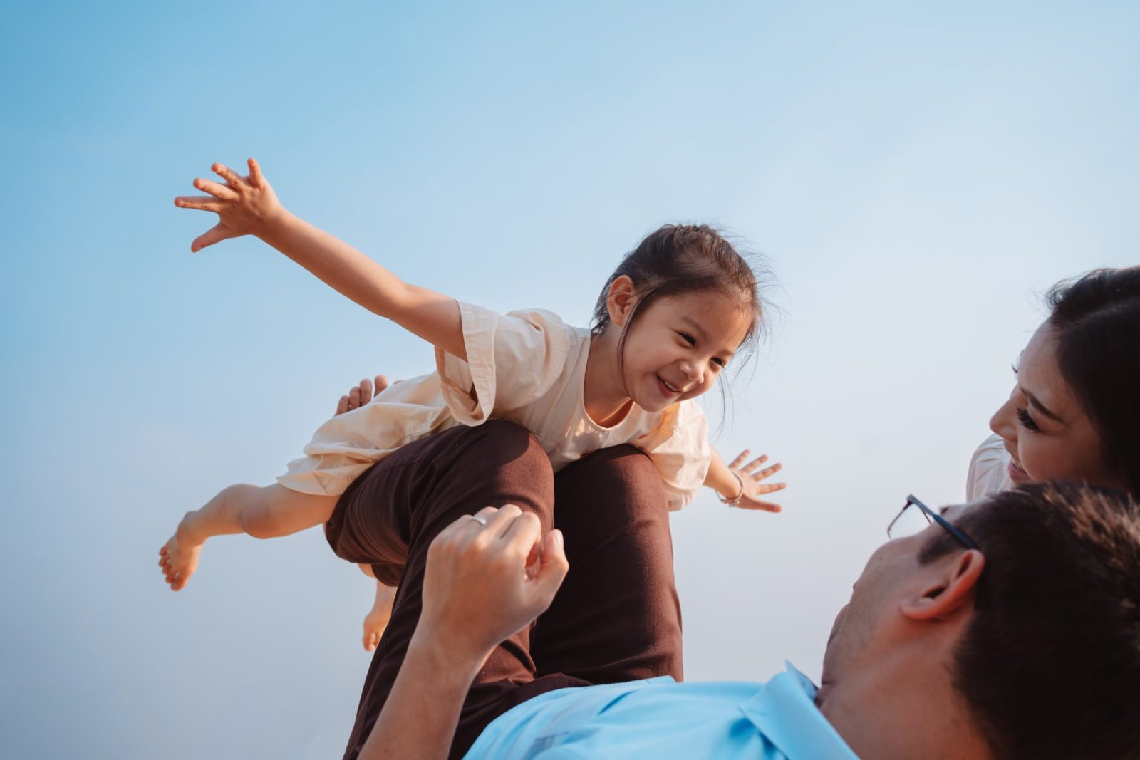 Insurance Agency Web Design Parents playing with their daughter under a clear blue sky